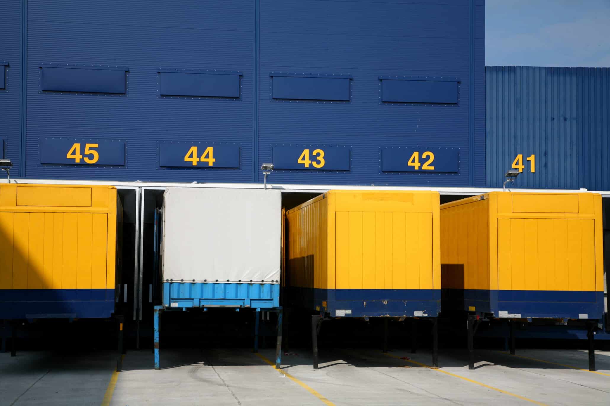 Außenansicht eines Logistik Zentrums mit Lager-Nummern und vier Containern davor