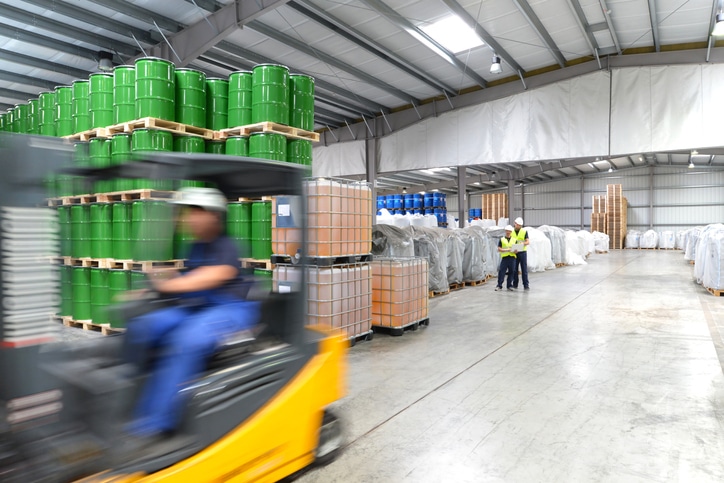 Staplerfahrer während des Zeitarbeiteinsatzes in einer Logistikhalle mit Chemikalien